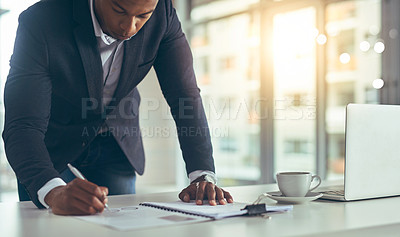 Buy stock photo Cropped shot of a young businessman taking notes while working in his modern office
