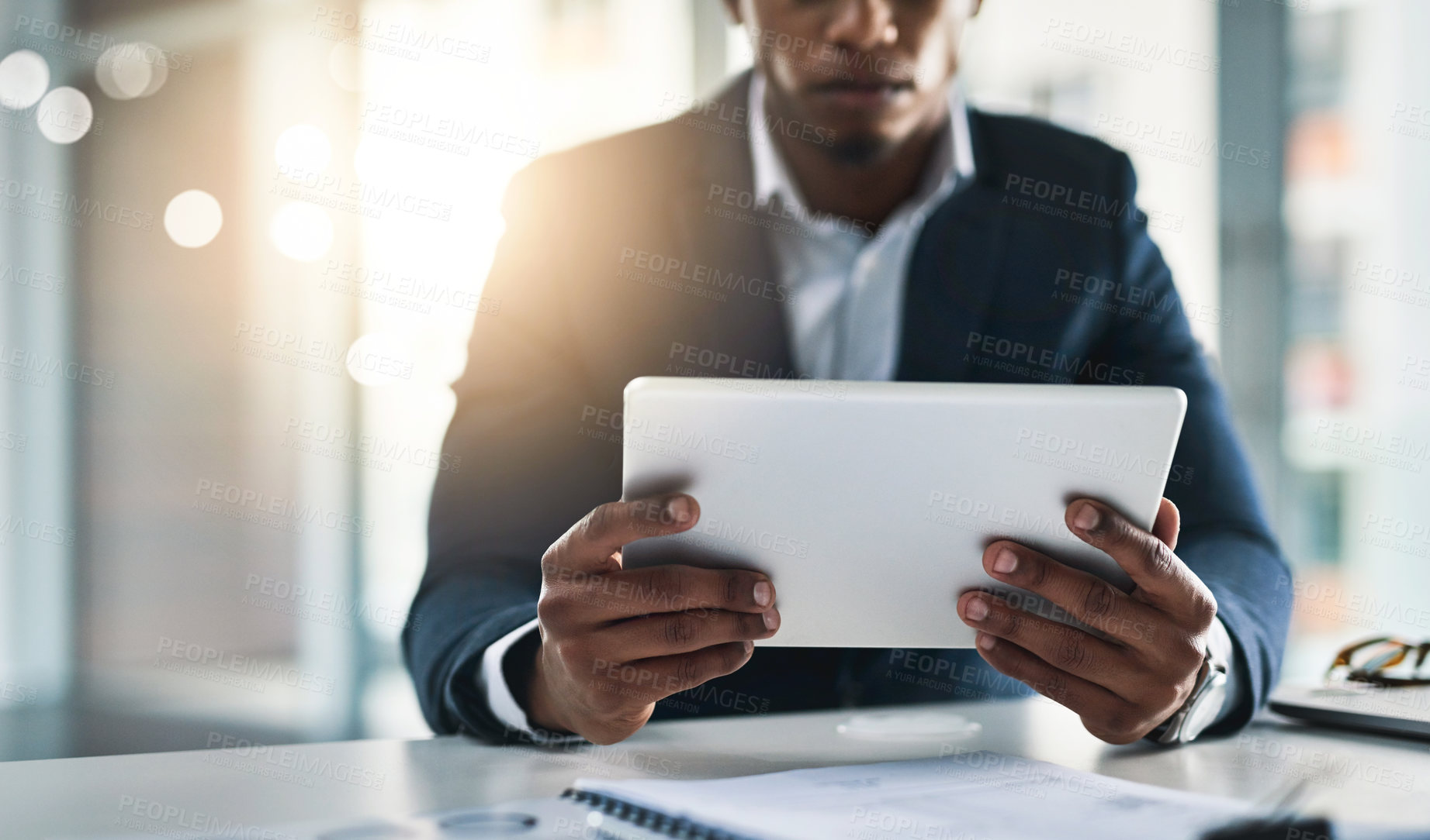 Buy stock photo Cropped shot of a young businessman working on his tablet in a modern office