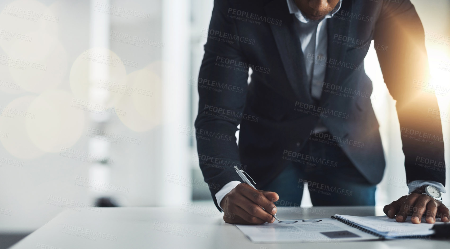 Buy stock photo Cropped shot of an unrecognizable young businessman taking notes while working in his modern office