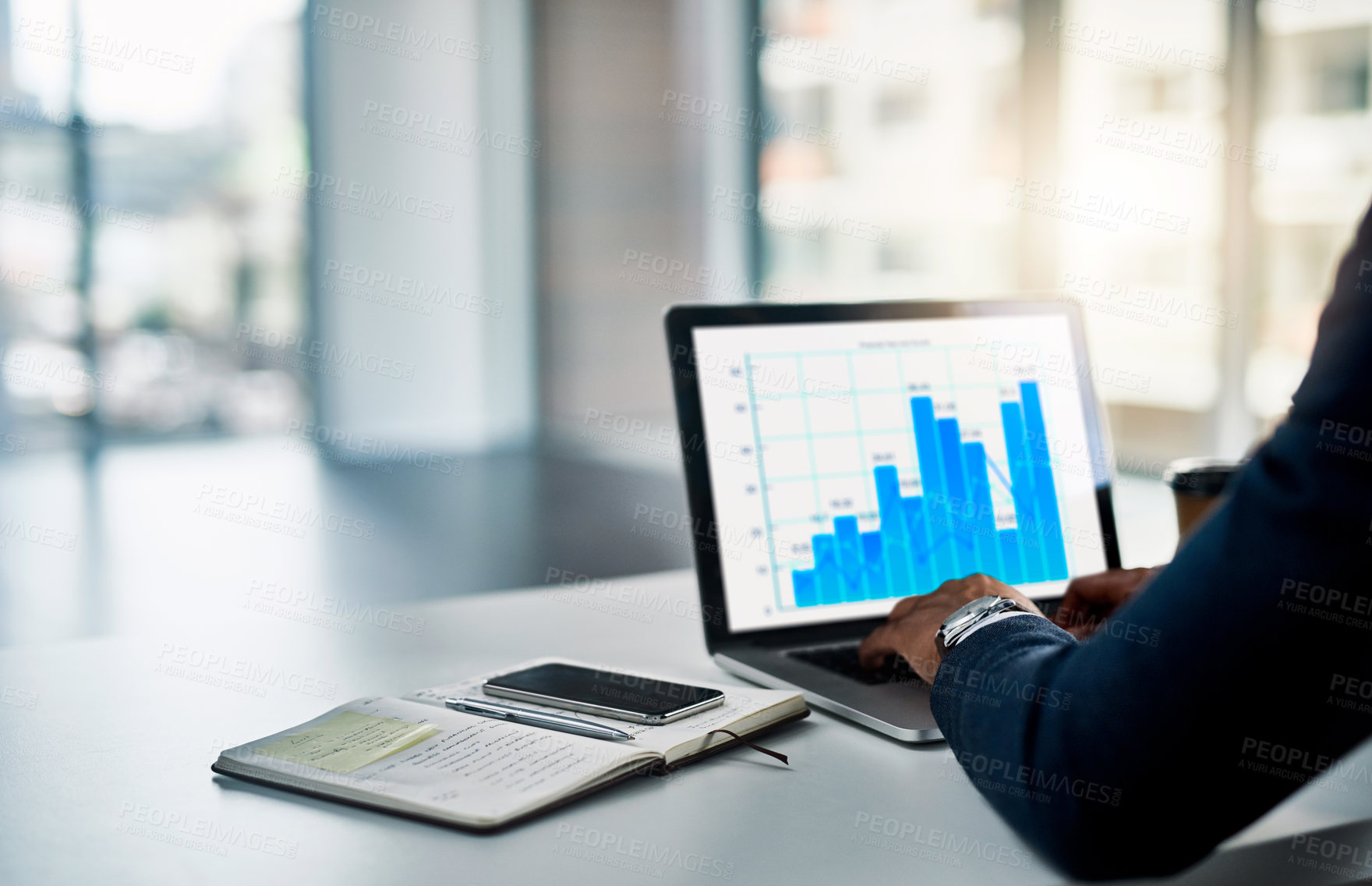 Buy stock photo Cropped shot of an unrecognizable young businessman working on his laptop in a modern office