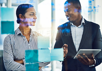 Buy stock photo Shot of two businesspeople brainstorming with notes on a glass wall in an office