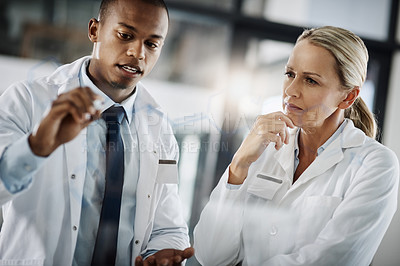 Buy stock photo Cropped shot of two scientists writing down formulas on a glass wipe board while doing research in their lab