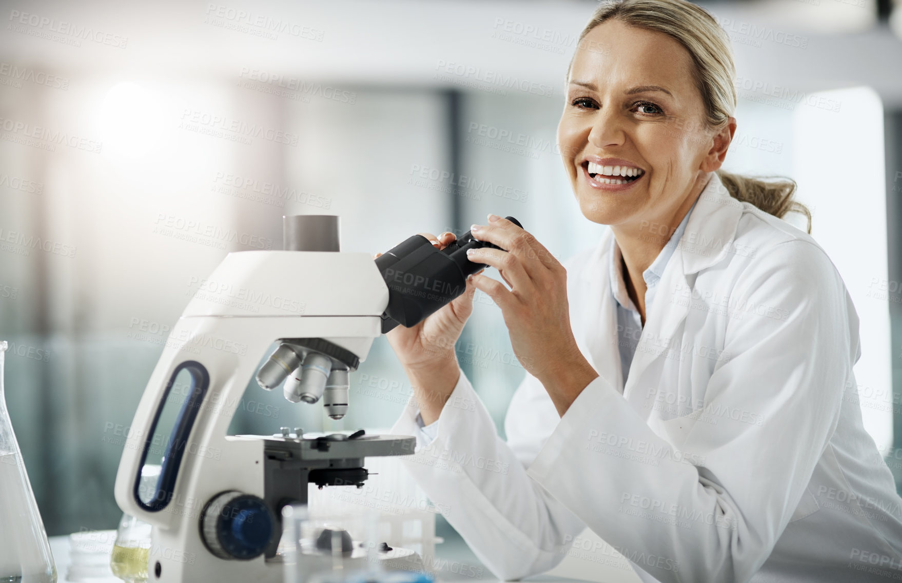 Buy stock photo Cropped portrait of an attractive mature female scientist using a microscope while doing research in her lab