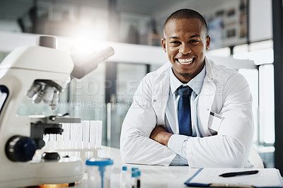 Buy stock photo Cropped portrait of a handsome young male scientist sitting with his arms folded in his research lab
