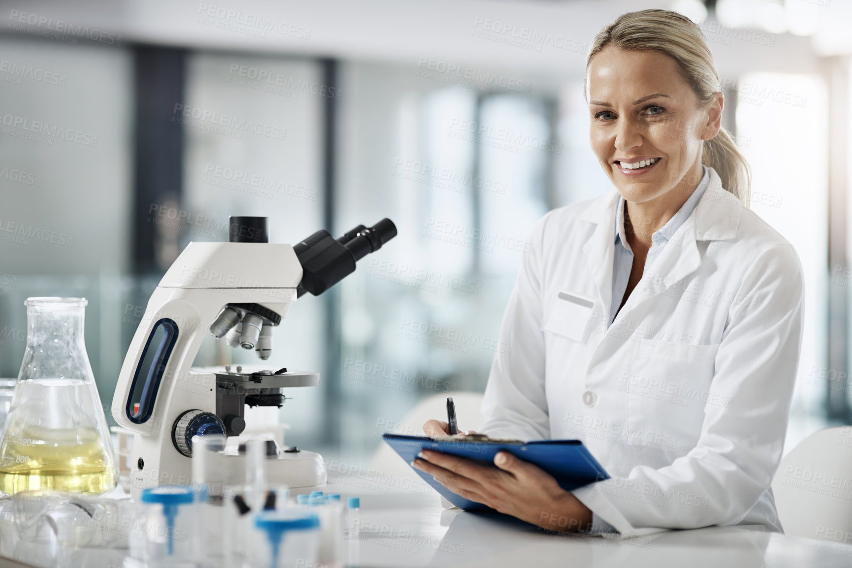 Buy stock photo Cropped portrait of an attractive mature female scientist taking down notes while doing research in her lab