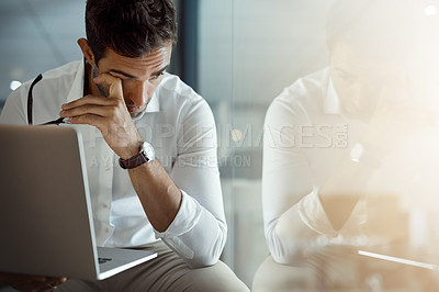 Buy stock photo Cropped shot of a young businessman looking stressed while working on his laptop in the office