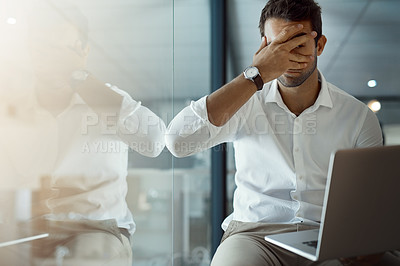 Buy stock photo Cropped shot of a young businessman looking nervously through his fingers at his laptop screen while working in his office
