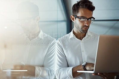 Buy stock photo Cropped shot of a handsome young businessman working on his laptop in the office
