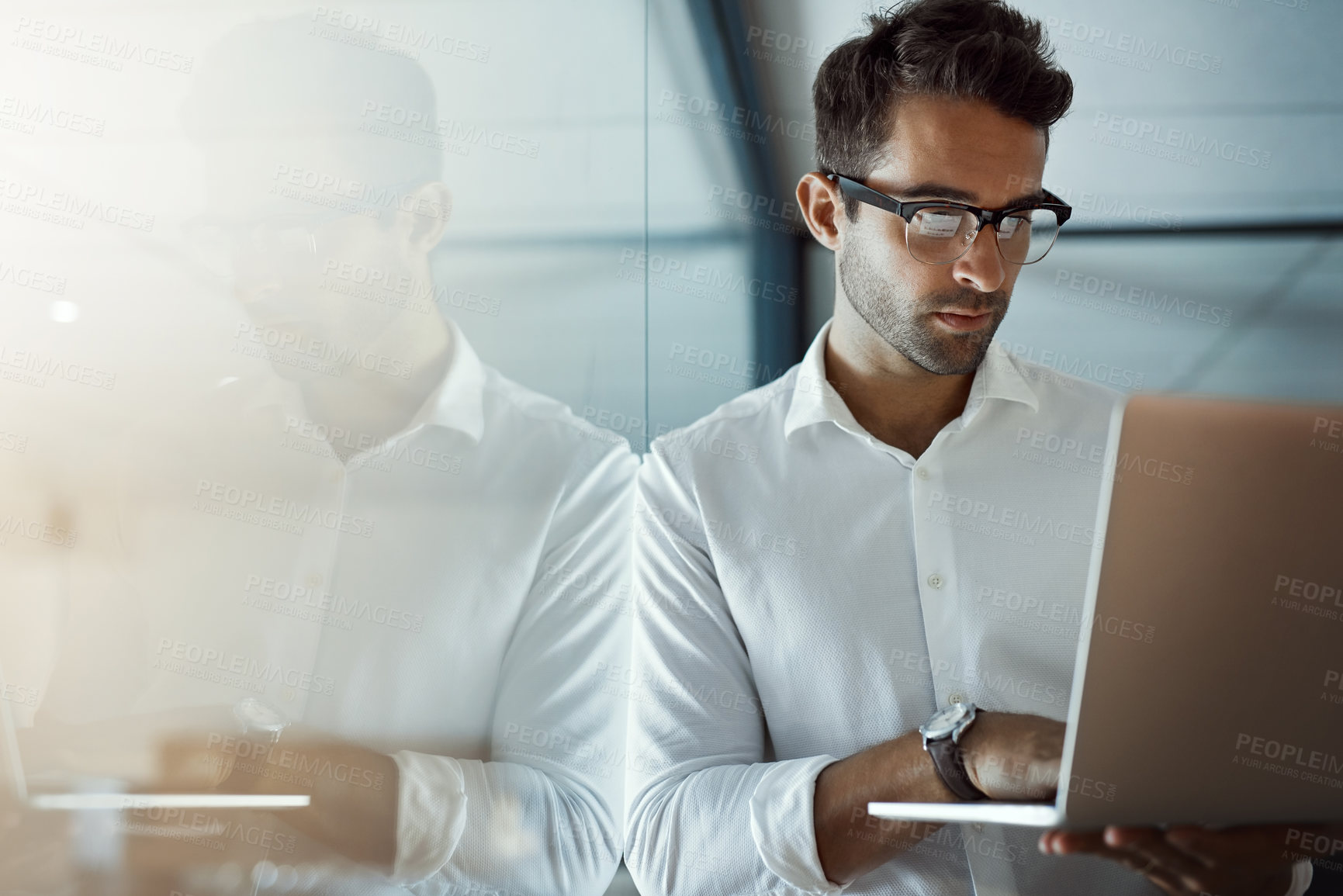 Buy stock photo Cropped shot of a handsome young businessman working on his laptop in the office