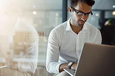 Buy stock photo Cropped shot of a handsome young businessman working on his laptop in the office