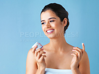 Buy stock photo Woman, smile and skincare or cream product on blue background for treatment, dermatology or mockup. Female person, moisturizing and jar for sunscreen protection with studio, cosmetics or thinking