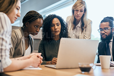 Buy stock photo Shot of a group of focussed businesspeople browsing on a laptop together in the office at work during the day