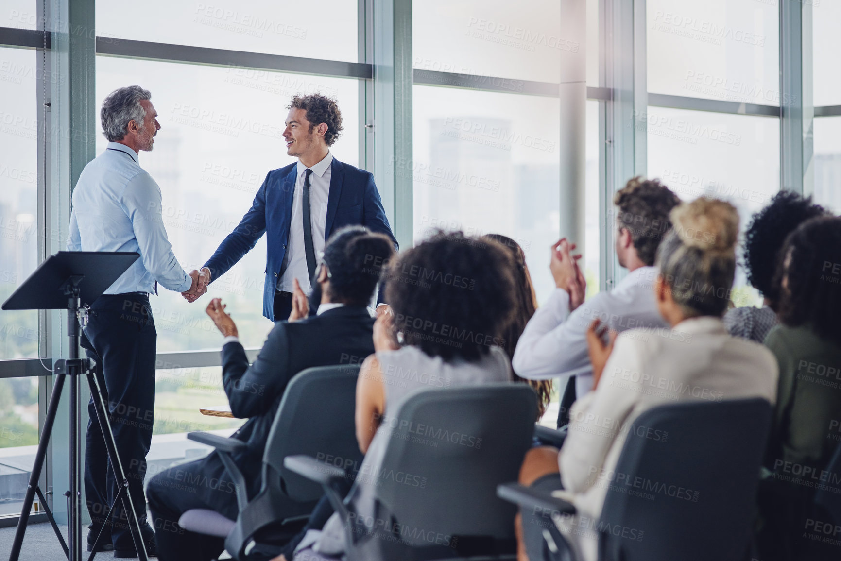 Buy stock photo Cropped shot of two businessmen shaking hands during a seminar in the conference room