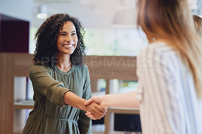 Buy stock photo Low angle shot of two young businesswomen shaking hands during a meeting in the boardroom