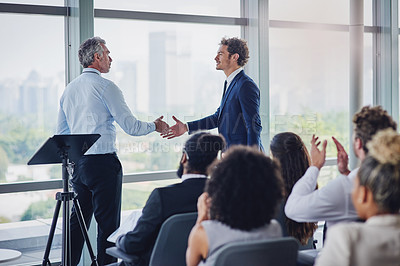Buy stock photo Cropped shot of two businessmen shaking hands during a seminar in the conference room