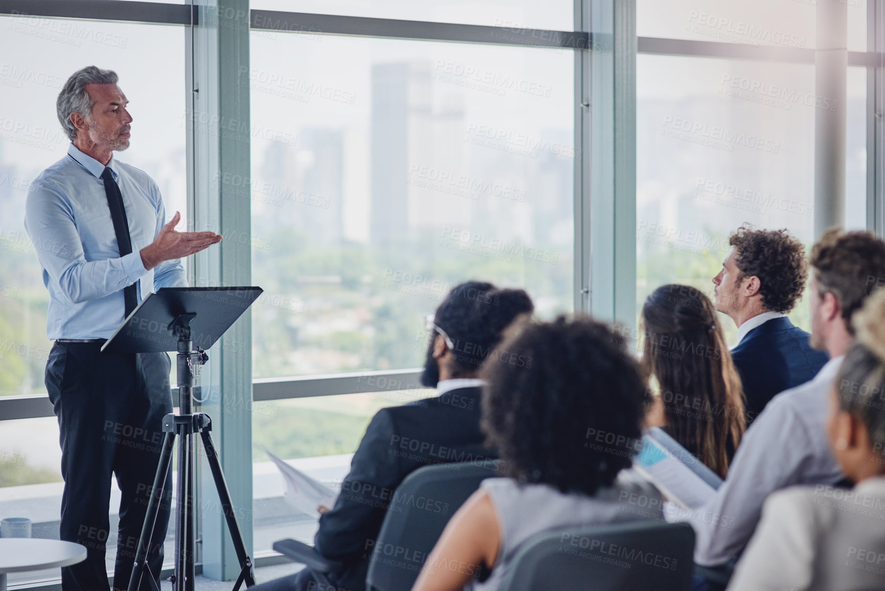 Buy stock photo High angle shot of a handsome mature male speaker addressing a group of businesspeople during a seminar in the conference room