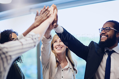 Buy stock photo Low angle shot of a group of young businesspeople high fiving in celebration while standing in their office