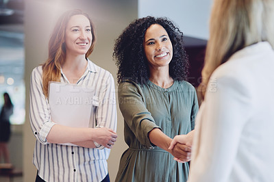 Buy stock photo Cropped shot of two young businesswomen shaking hands during a meeting in the boardroom