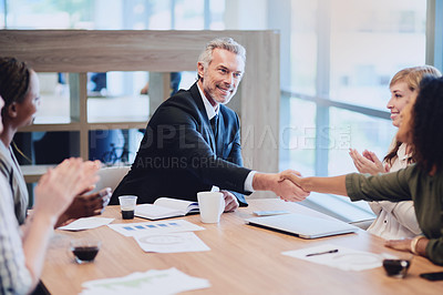 Buy stock photo High angle shot of two businesspeople shaking hands during a meeting in the boardroom