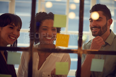 Buy stock photo Cropped shot of young businesspeople brainstorming on a glass wall in the office