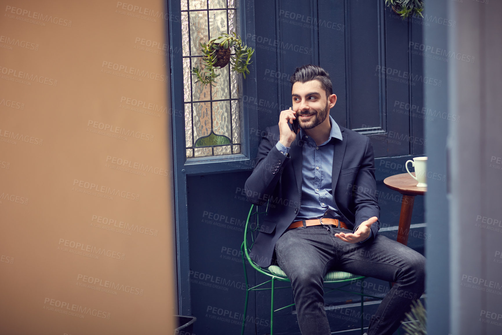 Buy stock photo Cropped shot of a young handsome businessman on a call at a cafe