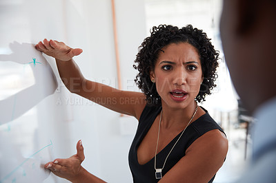 Buy stock photo Cropped shot of a young businesswoman explaining information on a whiteboard to her male colleague in the office