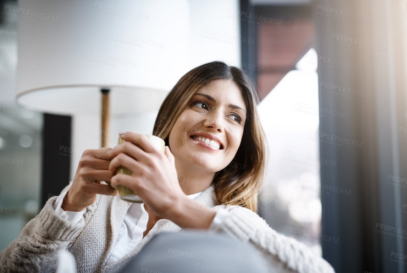 Buy stock photo Cropped shot of a young woman enjoying a cup of coffee while relaxing at home