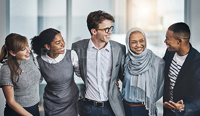 Buy stock photo Shot of a group of young cheerful businesspeople standing with arms around inside of the office at work during the day
