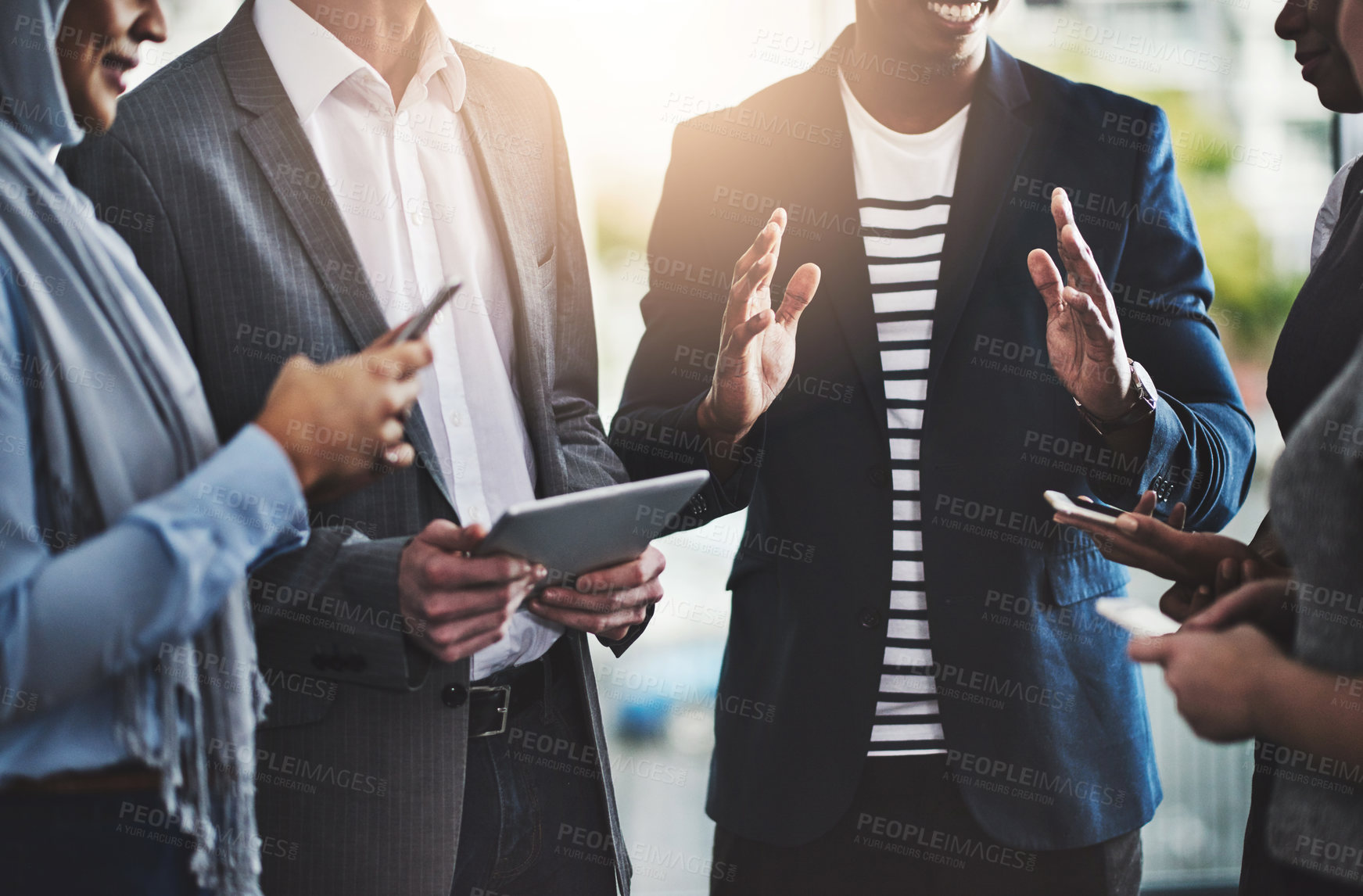 Buy stock photo Shot of a group of unrecognizable businesspeople browsing on digital devices while working together in the office at work