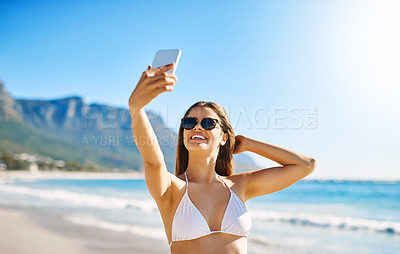 Buy stock photo Shot of a beautiful young woman taking a selfie on the beach