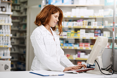 Buy stock photo Shot of a young pharmacist working on a computer in a chemist