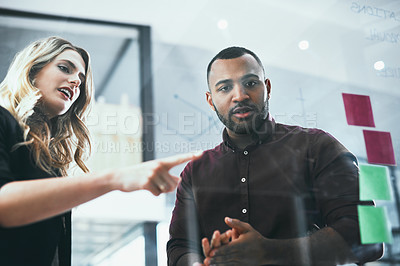 Buy stock photo Shot of a young businessman and businesswoman brainstorming in a modern office