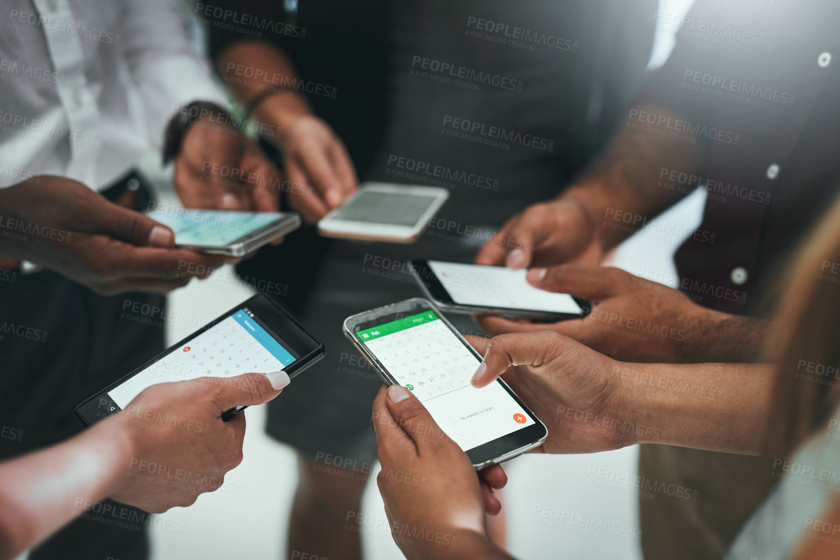 Buy stock photo Cropped shot of a group of businesspeople using their mobile phones together
