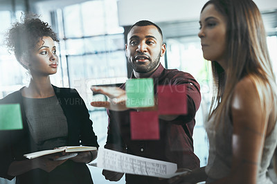 Buy stock photo Shot of a group of young businesspeople brainstorming in a modern office