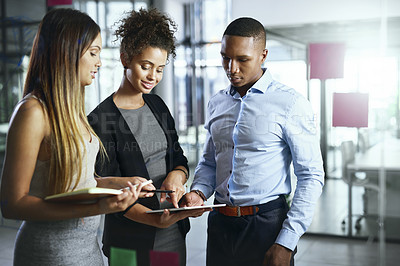 Buy stock photo Shot of a group of young businesspeople using a digital tablet together in a modern office