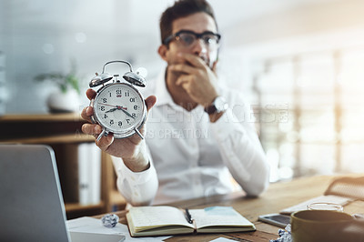 Buy stock photo Portrait of a young businessman looking stressed out while holding a clock in an office