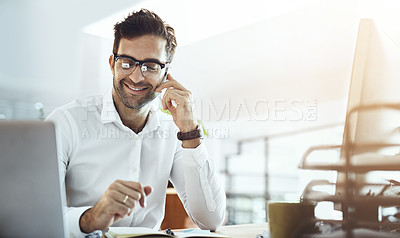 Buy stock photo Shot of a young businessman talking on a cellphone while working in an office