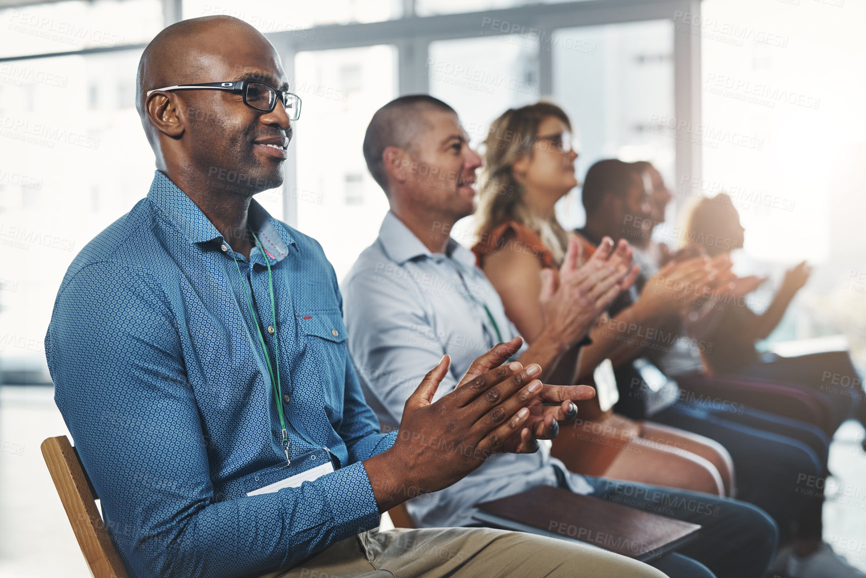 Buy stock photo Employees sitting and clapping together in a seminar and successful workshop. Diverse workplace that support the staff with a training conference. Celebrating professional relationships in business.