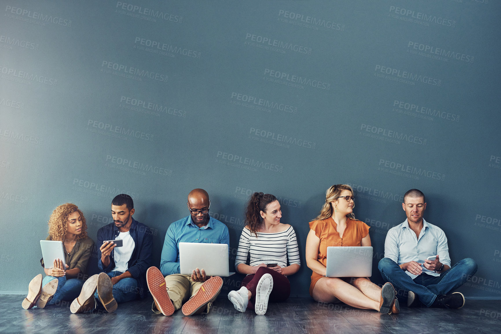Buy stock photo Diverse digital team exploring online platform on many devices, sitting against copy space together. Social advertising and global networking, collaborating with technology, connecting global network
