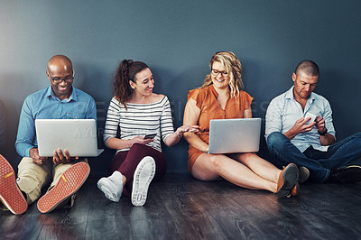 Buy stock photo Smiling, diverse group of casual and modern business people with their digital devices on social media networking apps. Happy, connected team of colleagues sitting, working on laptop pcs and phones 