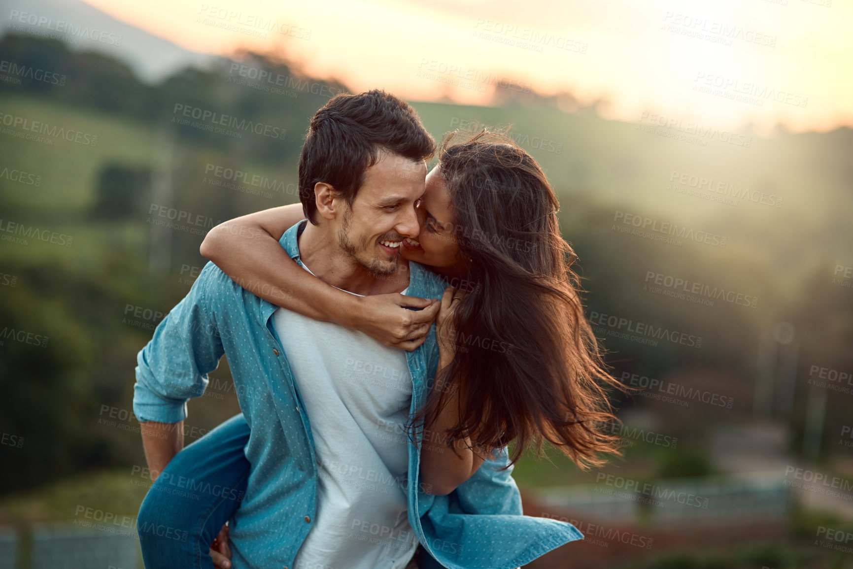 Buy stock photo Cropped shot of a handsome young man piggybacking his girlfriend while spending some time outdoors