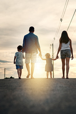 Buy stock photo Rearview shot of an unrecognizable family walking together in the neighbourhood