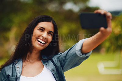 Buy stock photo Shot of an attractive young woman taking selfies using a mobile phone in a park