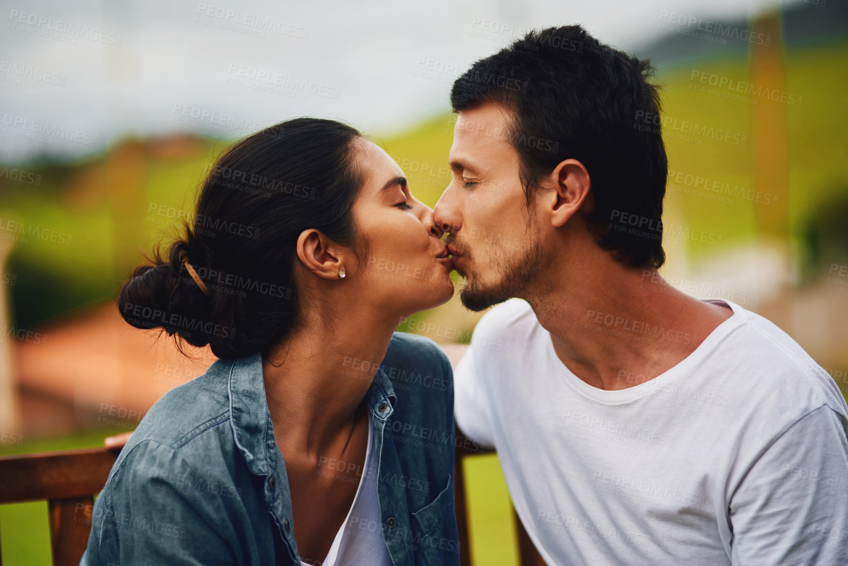 Buy stock photo Shot of an affectionate young couple kissing in the park
