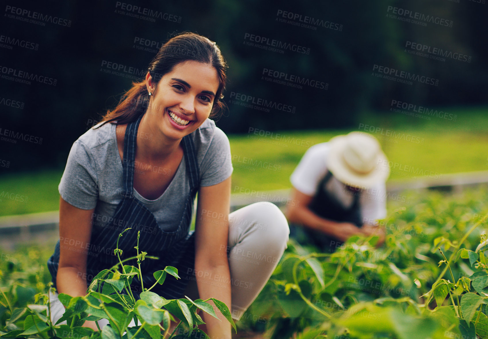 Buy stock photo Portrait of a young woman working in a garden with her husband in the background