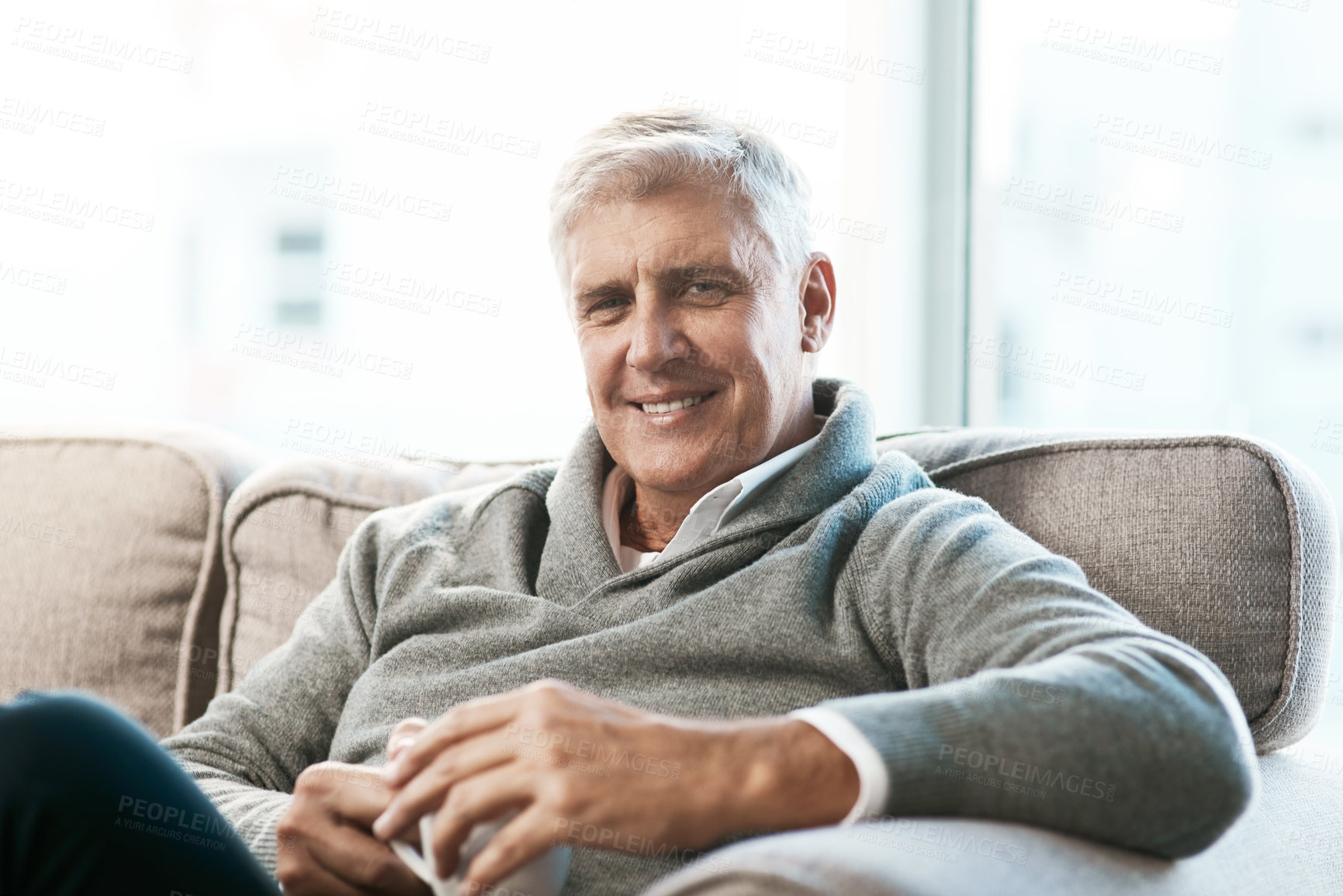Buy stock photo Cropped portrait of a handsome mature man enjoying a coffee while relaxing on the sofa at home