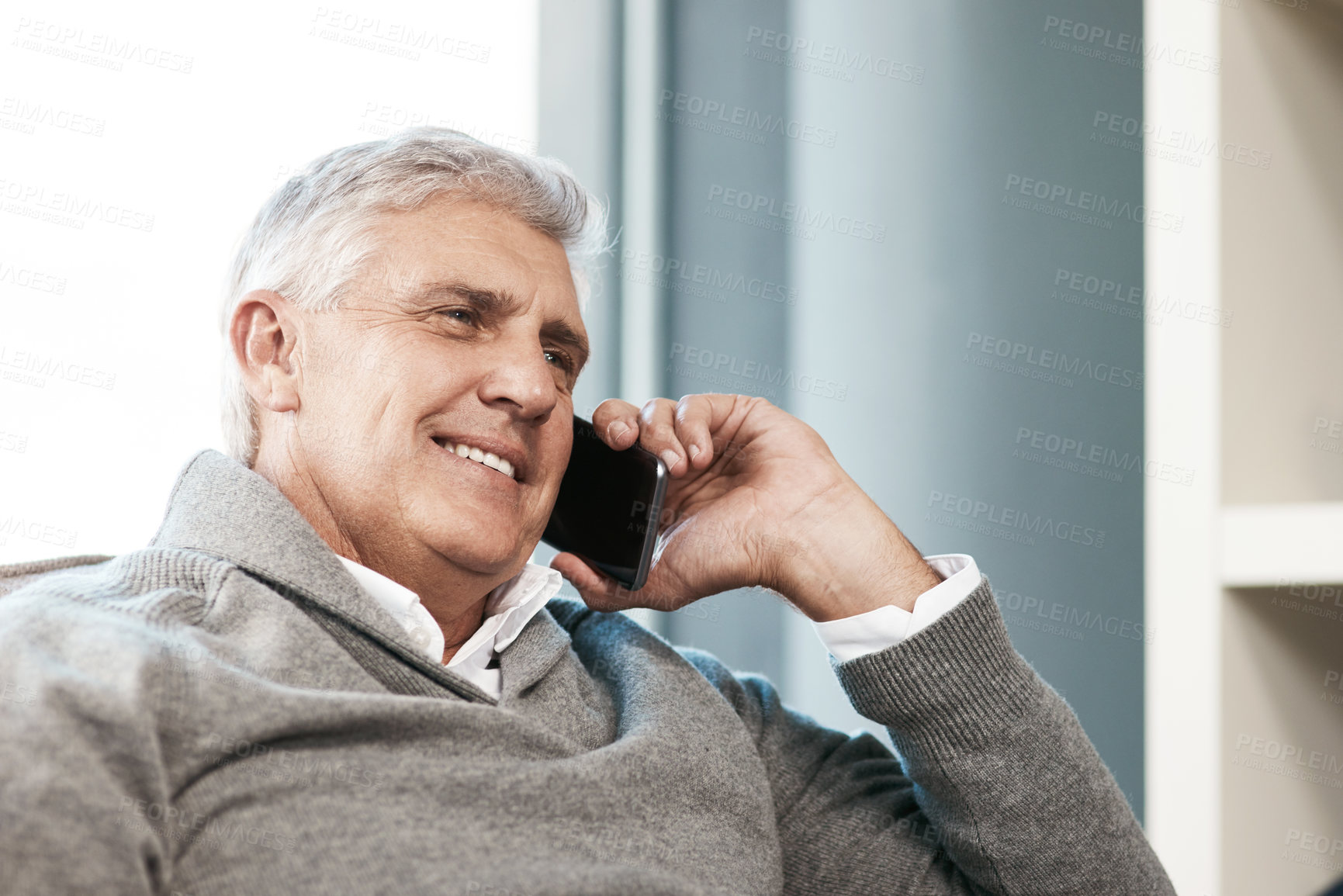 Buy stock photo Cropped shot of a handsome mature man making a phonecall while relaxing on the sofa at home