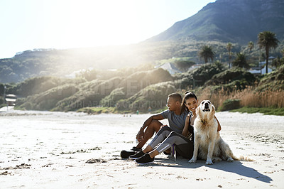 Buy stock photo Shot of a sporty young couple taking a break with their dog while exercising at the beach