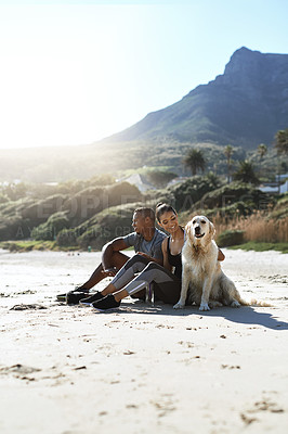 Buy stock photo Shot of a sporty young couple taking a break with their dog while exercising at the beach