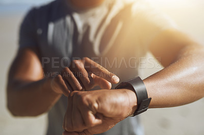 Buy stock photo Closeup shot of an unrecognizable man checking his smartwatch while exercising outdoors